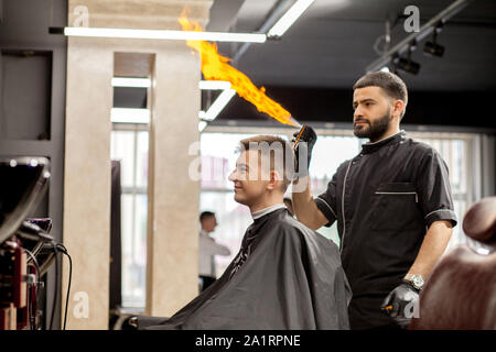 Guy brutale dans un salon de coiffure moderne. Coiffure coiffure rend un homme . Coiffure coiffure avec maître n'tondeuse à cheveux. Concept de coiffure Banque D'Images