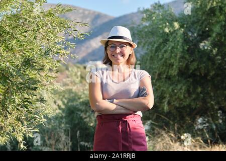 Portrait de femme de confiance avec le propriétaire de la ferme d'olive, les bras croisés, l'arrière-plan d'oliviers dans les montagnes, les olives eco pour l'alimentation et la cosmétologie Banque D'Images