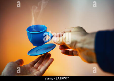 Bleu flottant espresso avec les mains. Vue à la première personne. Maquette de planeur dans l'air tasse de café chaud. Concept léviter Banque D'Images