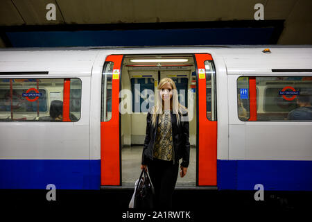 Portrait d'une belle jeune femme avec une rame de métro à l'arrière-plan au centre-ville de Londres, Royaume-Uni Banque D'Images