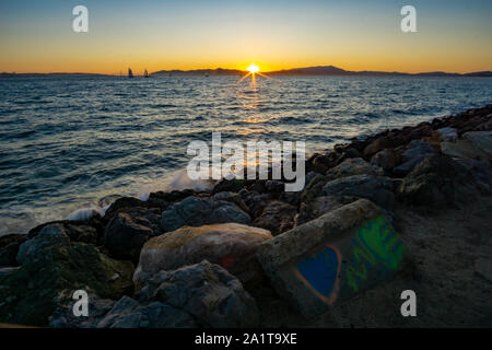 Coucher de soleil sur la baie avec l'inscription 'love me' écrit à la craie sur un rocher au premier plan. Banque D'Images