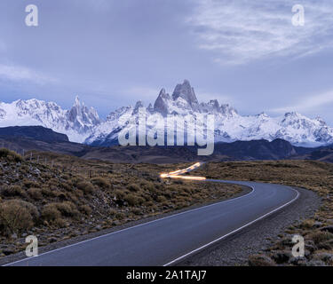 La route d'El Chalten avec sentiers de lumière de voiture sur la route et le mont fitzroy et Cerro Torre en arrière-plan Banque D'Images