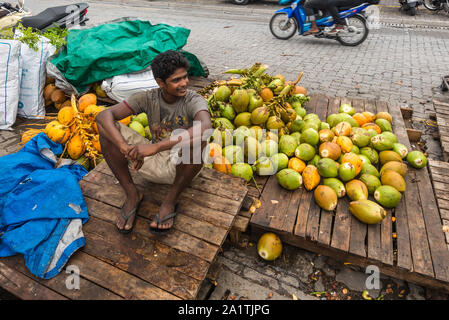Male, Maldives - Le 16 novembre 2017 : vendeur vend des noix de coco dans la rue par temps nuageux à Malé, capitale des Maldives. Homme Marché local dans les Maldives. Banque D'Images
