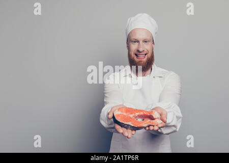 Portrait of attractive cheerful handsome nice confiant guy boucher positive tenant un poisson pièce dans la main du bras montrant prêts à préparer un plat de sushi Banque D'Images