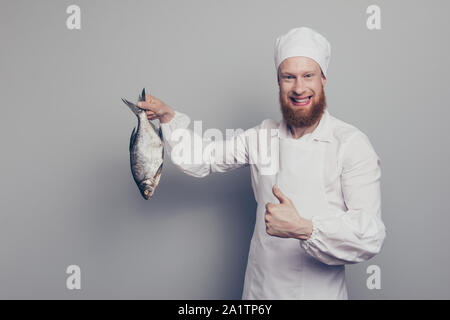 Portrait de il beau beau beau beau joyeux joyeux heureux guy boucher tenant un poisson dans la main du bras prêt à préparer de délicieux mets délicieux montrant Banque D'Images