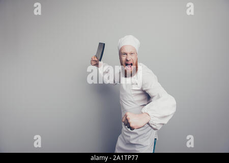 Portrait de crazy mad butcher attrayant beau guy holding couteau en main bras agression menaçant sur fond gris pastel isolés Banque D'Images