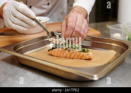 Chef, c'est la sauce herbes sur le saumon grillé steak pour faire une croûte salés Banque D'Images