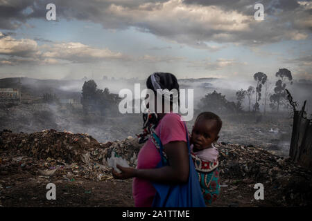 Une femme portant son bébé regarde vers le bas le dépotoir de Dandora, sur le bord du bidonville de Korogocho dans la capitale Nairobi, Kenya. Banque D'Images