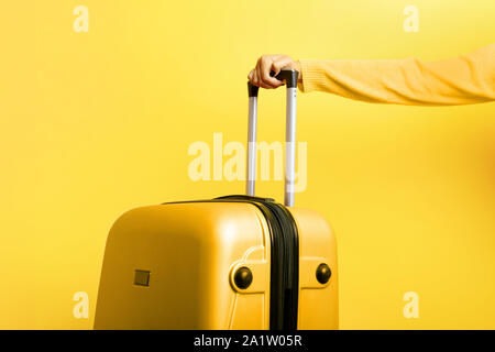 Femme tenant une valise à la main jaune sur fond jaune, travel concept Banque D'Images