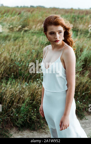 Jeune et Jolie femme rousse en robe blanche à l'extérieur Banque D'Images