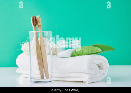 Bambou en bois des brosses à dents en verre, le bicarbonate de soude et serviette sur fond vert. Concept d'hygiène personnelle Banque D'Images