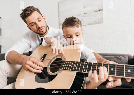 Père Fils d'enseignement à jouer la guitare acoustique à la maison Banque D'Images