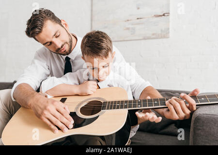 Père Fils d'enseignement à jouer la guitare acoustique à la maison Banque D'Images