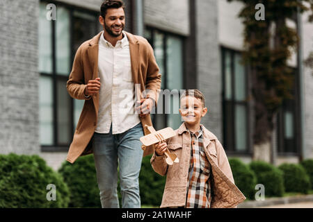 Smiling dad en manteau et fils avec toy avion fonctionnant sur street Banque D'Images