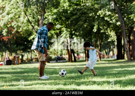 Handsome african american man playing football avec mignon fils Banque D'Images