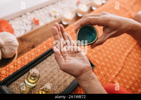 Portrait de verser de l'huile parfum masseur sous la main Banque D'Images