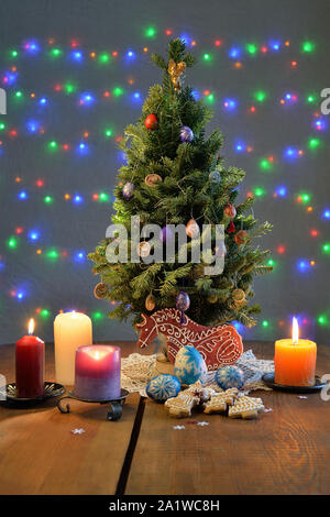 Arbre de Noël entouré par les bougies, les cookies et les oeufs sur la table Banque D'Images