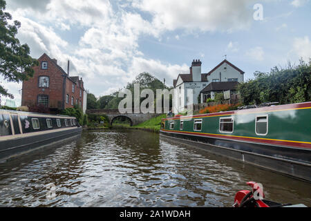 Bateaux, barges ou étroite, près du village de Gnosall sur le Shropshire Union Canal en Angleterre, avec le pont de briques et Inn Navigation derrière. Banque D'Images