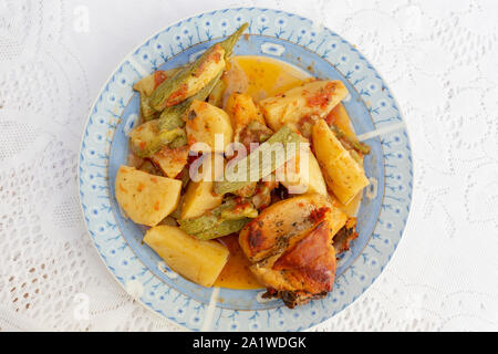 Une authentique Assiette de poulet au four crétois avec des pommes de terre et courgettes (zuccini) dans une riche sauce tomate et sauce d'huile d'olive aux herbes Banque D'Images