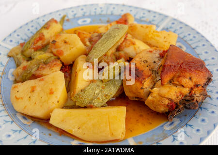 Une authentique Assiette de poulet au four crétois avec des pommes de terre et courgettes (zuccini) dans une riche sauce tomate et sauce d'huile d'olive aux herbes Banque D'Images