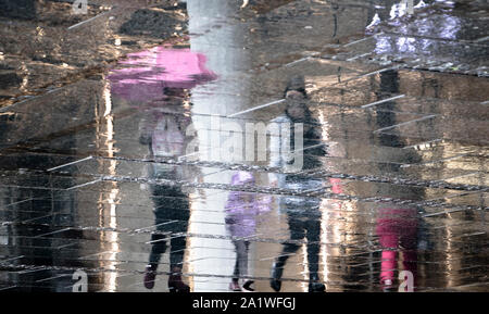 Réflexion floue ombre silhouette de personnes et un enfant de marcher ensemble sous un parapluie, un jour de pluie sur une rue de ville Banque D'Images