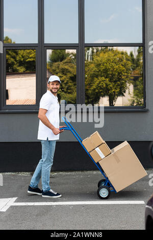 Heureux l'homme barbu debout avec livraison Livraison panier près du bâtiment Banque D'Images