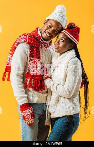 African American man en tenue d'hiver embracing woman qui le regardait isolé sur le jaune Banque D'Images