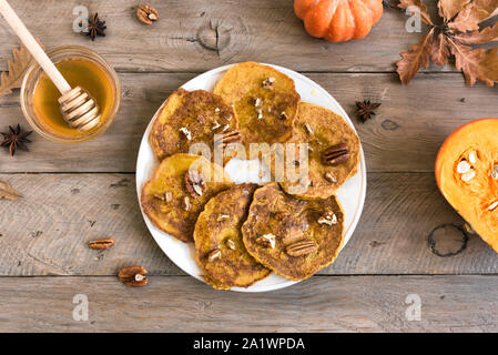 Crêpes à la citrouille et aux pacanes et le miel sur table en bois, vue du dessus, copiez l'espace. Petit déjeuner santé d'automne traditionnelle - crêpes à la citrouille. Banque D'Images