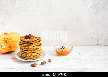 Crêpes à la citrouille et aux pacanes et miel sur la citrouille biologique tableau blanc, copie de l'espace. Pile de crêpes à la citrouille. Banque D'Images