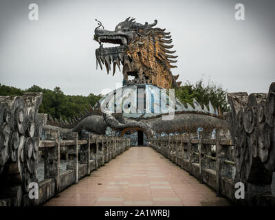 Immense et effrayant dragon en pierre de pointes et bouche ouverte avec dents en vue de profil avec sentier au parc aquatique abandonné, Thuy Tien lake, Hue, Vietnam Banque D'Images