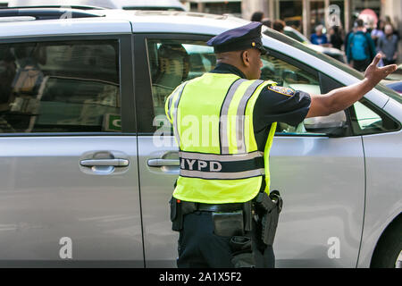 New York, 9/27/2019 : officier de la police de porter un gilet réfléchissant sur son uniforme est en communication avec un automobiliste lors de diriger le trafic de Manhattan. Banque D'Images