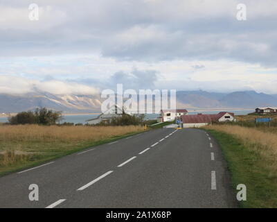 La pittoresque route à travers le Parc National Snaefellsjokull avec quelques logements et le glacier, parées de volcan dormant dans la distance. Banque D'Images