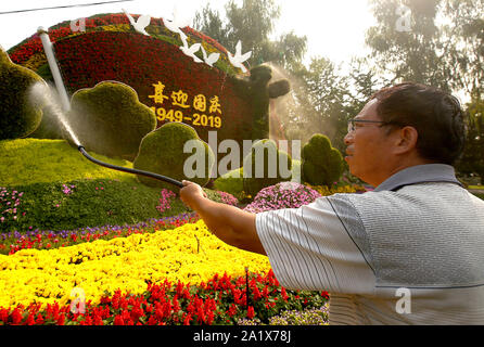 Beijing, Chine. Sep 29, 2019. Un travailleur chinois eaux une parterre de célébrer le prochain 70e anniversaire de la RPC, le dimanche, 29 Septembre, 2019. Capitale de la Chine a été décorée de fleurs, et des slogans patriotiques affiche communiste alors qu'il prépare le 1 octobre anniversaire. Photo par Stephen Shaver/UPI UPI : Crédit/Alamy Live News Banque D'Images