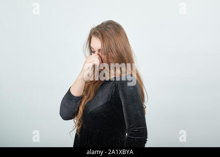 Fille aux cheveux brun en robe noire sur fond blanc isolé montre les émotions Banque D'Images