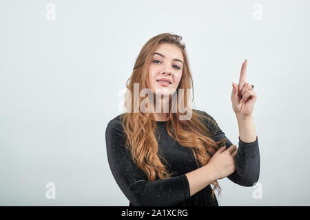 Fille aux cheveux brun en robe noire sur fond blanc isolé montre les émotions Banque D'Images