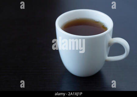 Dans une tasse de thé blanc et d'une théière blanche sur fond sombre Banque D'Images