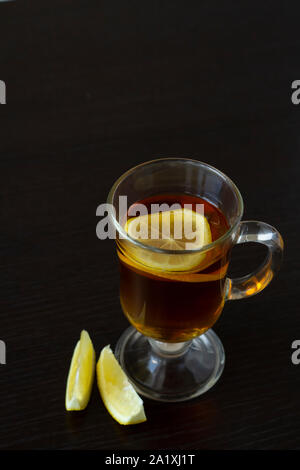 Thé au citron dans une tasse en verre sur fond sombre Banque D'Images