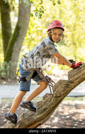 Jardin d'escalade, randonnées cours, garçon, 9 ans, avec casque et harnais, sur un parcours dans une forêt, Banque D'Images