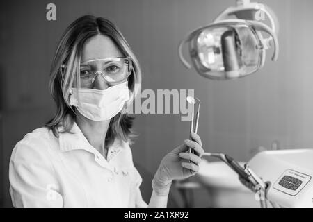 Portrait de femme médecin dentiste avec instrument en cabinet dentaire, photo en noir et blanc. Banque D'Images