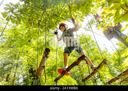 Jardin d'escalade, randonnées cours, garçon, 9 ans, avec casque et harnais, sur un parcours dans une forêt, Banque D'Images