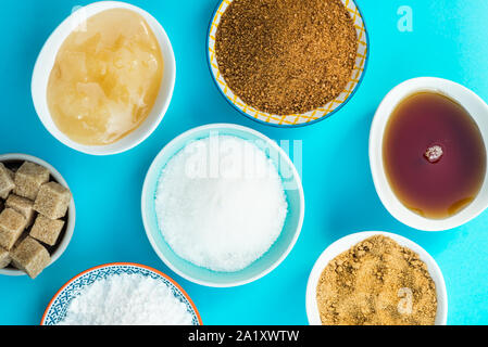 Différents types de Sucre et édulcorants dans les bols, tels que noix de coco, canne à sucre pur, le glaçage, le sirop d'érable, sucre mou brun foncé, miel, cubes démérara Banque D'Images