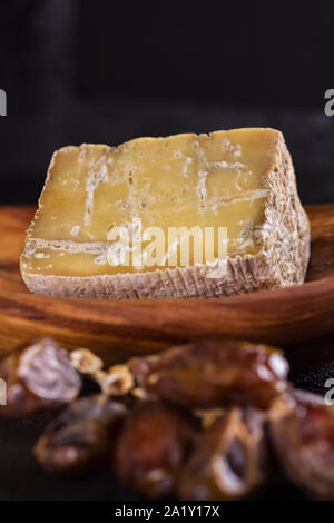 Vieux morceau de fromage bleu et une succursale de dates se situent sur un plat en bois Banque D'Images