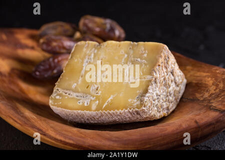 Vieux morceau de fromage bleu et une succursale de dates se situent sur un plat en bois Banque D'Images