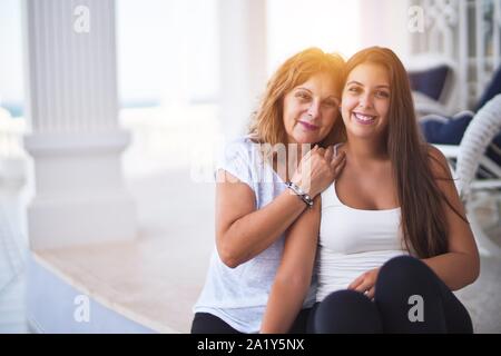 Belle Mère et fille assis à terrasse hugging and smiling Banque D'Images