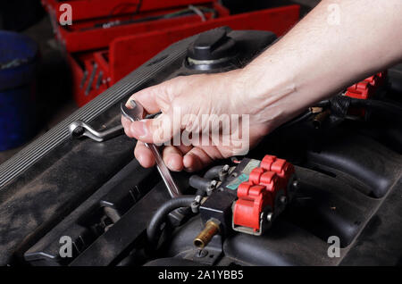 Car service - Réfection moteur, mécanicien à l'aide d'une clé à la main l'écrou tourne sur le collecteur d'admission Banque D'Images