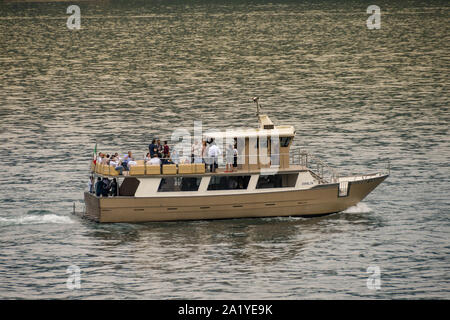 Le lac de Côme, Italie - Juin 2019 : un bateau à moteur sur le lac de Côme avec les gens à un événement social sur ses ponts. Banque D'Images