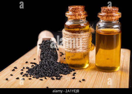 Pression à froid, en bonne santé l'huile de cumin noir. Ingrédients pour une alimentation saine dans une cuisine moderne. Fond sombre. Banque D'Images