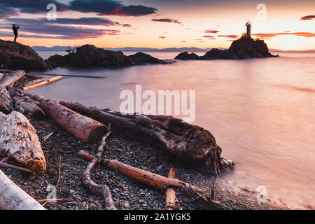 Plage rocheuse de soleil le long de la côte Pacifique du nord-ouest de l'île de Bowen à Howe Sound avec de spectaculaires vues sur le phare de l'ensemble juste au large de la côte de Vancouver BC Banque D'Images