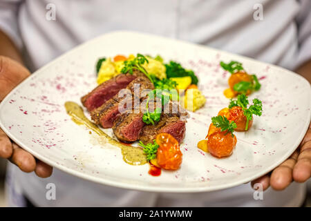 Chef de l'Afrique portent une plaque joliment décorer avec steak de surlonge et de tomates cerises Banque D'Images