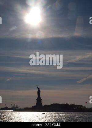 Statue de rétro-éclairé de la liberté dans le port de New York en septembre 2109. Grues de chargement à distance au Port de Bayonne (New Jersey). Banque D'Images